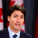 Trump’s SHOCKING Defense Board Pause – Canada Stunned! Man speaking in front of Canadian flags.