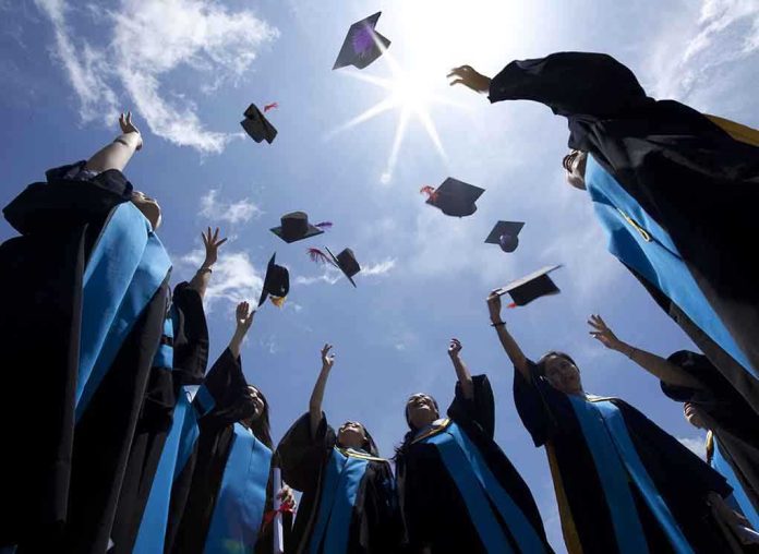 shutterstock_115335829 Graduating students celebrating by throwing their caps into the air under a bright blue sky