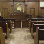 Justice Resigns Over Explosive Cheating Allegations! Interior view of an empty courtroom with wooden benches and a judges bench