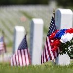 American flags and flowers placed at graves in a cemetery