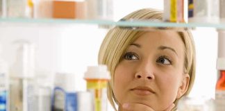 Menstrual Leave Fight Explodes—Hiring Panic Next? A woman thoughtfully looking at a medicine cabinet filled with various medications