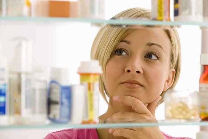 shutterstock_57590812 A woman thoughtfully looking at a medicine cabinet filled with various medications