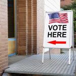 Voting Rights Rewritten In Los Angeles Vote Here sign with arrow and American flag.