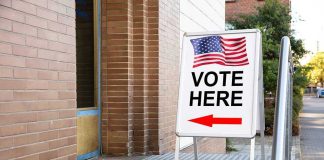 Voting Rights Rewritten In Los Angeles Vote Here sign with arrow and American flag.