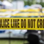 Iowa Family Massacre Stuns Town Yellow police line tape with Do Not Cross.