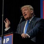 GOP Base Roars: America First Dominates Person speaking into microphone at a podium.