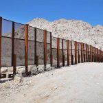 Cartel Super-Tunnel Found Under U.S. Port A long border wall stretches across a desert landscape with mountains in the background