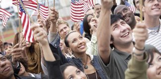 A diverse group of people joyfully waving American flags in celebration
