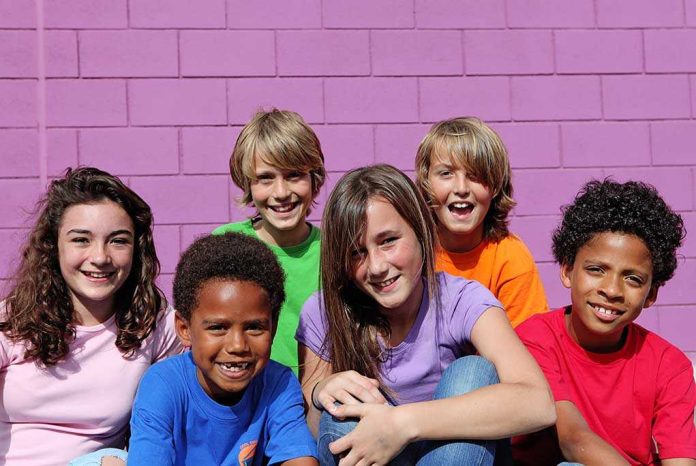 shutterstock_40854085 A group of six children smiling together in front of a purple wall