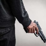 Mexico Town Hall Turned Killing Ground person holding a handgun at their side