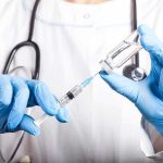 Ebola Emergency Escalates — First Vaccine Given Healthcare worker drawing vaccine from vial with syringe