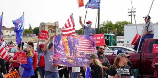 37-0? Inside Trump’s Scoreboard Crowd of people at a political rally holding flags and signs