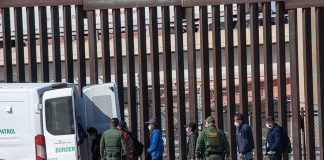 Border Meltdown in Spain Border agents escort a group near a tall fence and a patrol van