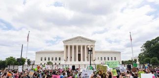 Crowd of protesters outside a neoclassical courthouse holding signs