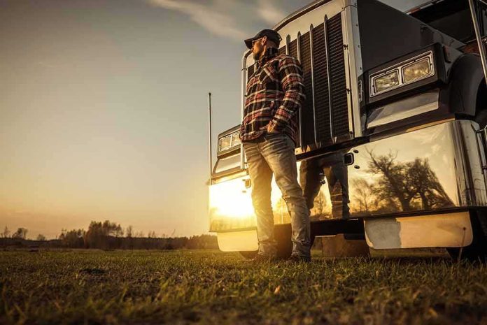 Truck driver standing beside a semi truck at sunset