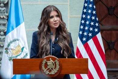 shutterstock_2646539471 A government official delivering a speech at a podium with flags in the background