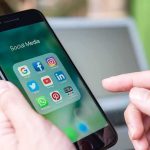 Burner Account Bombshell Hits Wisconsin Democrat Hands holding a smartphone with social media apps on screen