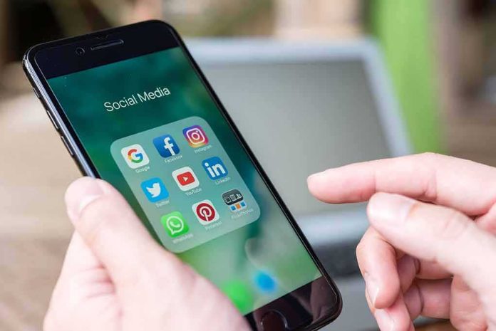 shutterstock_519587608 Hands holding a smartphone with social media apps on screen