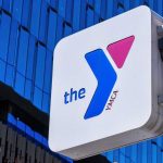 Gender Policy Vanishes — Why Now? YMCA sign mounted on a modern glass building