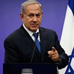 Assassins At The Door—Netanyahu’s Chilling Claim man in suit speaking at podium with Israeli flag