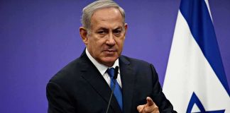 Assassins At The Door—Netanyahu’s Chilling Claim man in suit speaking at podium with Israeli flag
