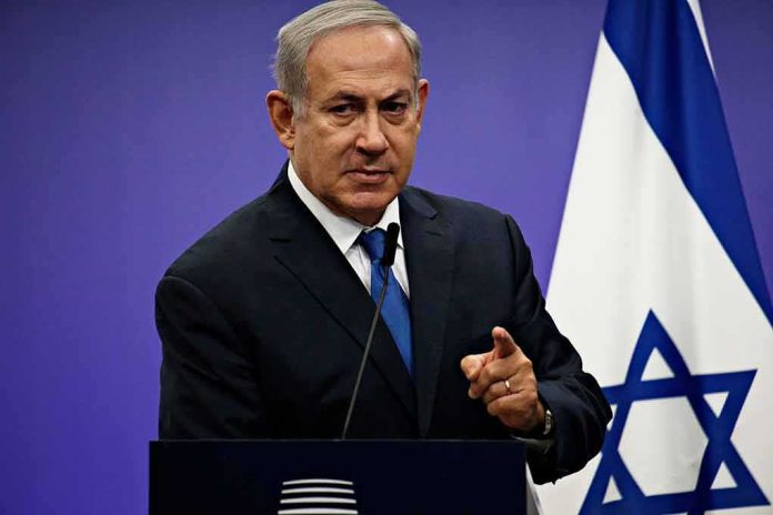 man in suit speaking at podium with Israeli flag