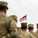 Bounty Threat Escalates Tehran Standoff U.S. flag flying above a formation of soldiers in uniform