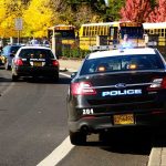 Mass-Shooting Suspect Walks Days Before School Police cars with lights on near school buses on a city street