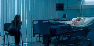 hospital room with child in bed and adult sitting nearby
