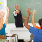 Grade Tampering Bombshell Hits Nashville Students raising hands in a classroom while teacher points