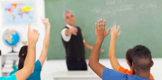 Grade Tampering Bombshell Hits Nashville Students raising hands in a classroom while teacher points