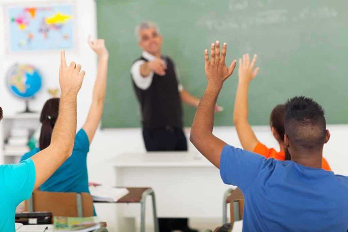 Students raising hands in a classroom while teacher points
