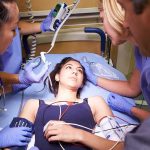 TV Anchor’s Heart Scare After Boosters Patient on hospital gurney surrounded by medical staff