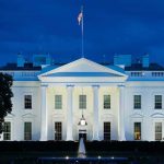 Chilling Iran Broadcast Names Barron Trump White House illuminated at dusk with flagpole and columns