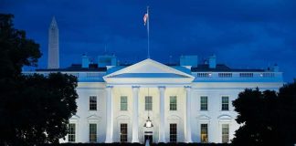 White House illuminated at dusk with flagpole and columns