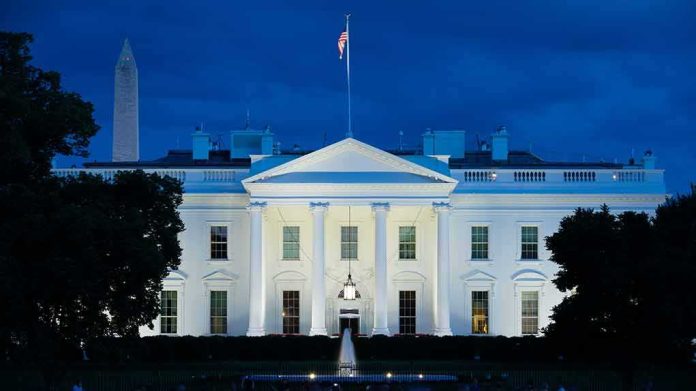 shutterstock_1817955236 White House illuminated at dusk with flagpole and columns