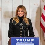 Melania’s Back-Channel With Putin? woman speaking at podium with microphones and US flags