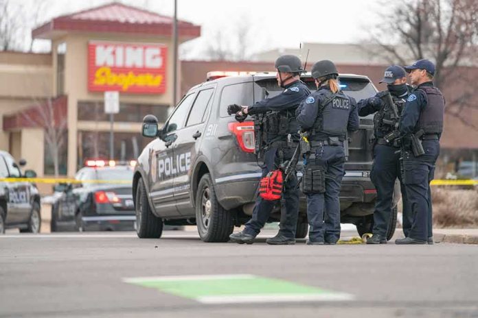 Police officers gather beside a patrol SUV at a taped-off scene
