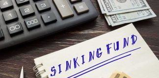 Notebook labeled sinking fund beside cash, calculator, and pen