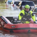 Raging Waters Trap Dozens In Indy Rescue worker in an inflatable boat during urban flooding