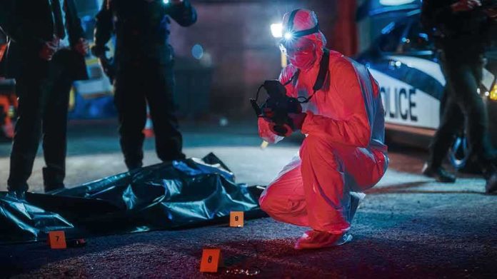 forensic investigator photographs crime scene evidence at night