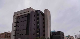 Wanted By U.S., Governor Reclaims Power Modern concrete and dark glass government building on a cloudy day