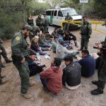 Record Bounty Hits U.S.-Born Kingpin Border agents surround a seated group near a van