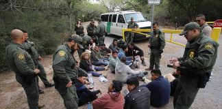 Record Bounty Hits U.S.-Born Kingpin Border agents surround a seated group near a van