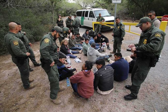 shutterstock_2268609071 Border agents surround a seated group near a van