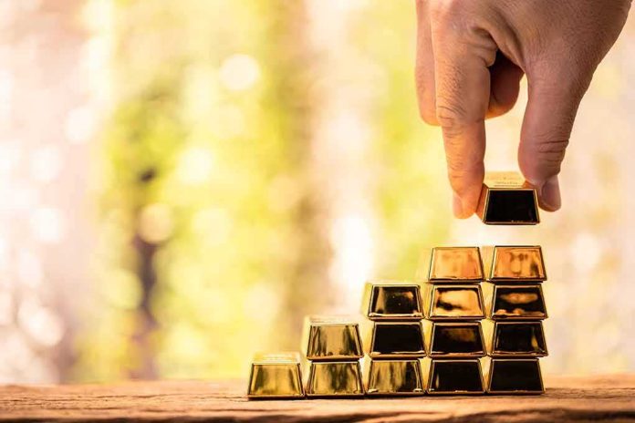 shutterstock_2272168865 Hand stacking small gold bars into a pyramid