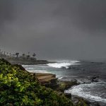 Malibu Mansion Uproar Engulfs Kamala Harris Rocky coastline with waves under dark storm clouds