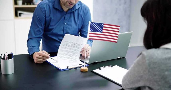 shutterstock_2276983393 Two people at a desk reviewing documents with a small American flag by a laptop
