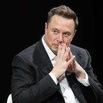Musk Reverses Course—Big Money Moves man in a suit with hands clasped thoughtfully