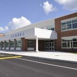 Federal Crackdown Looms On K-12 Gender Policies Modern school building with large windows and a clear sky